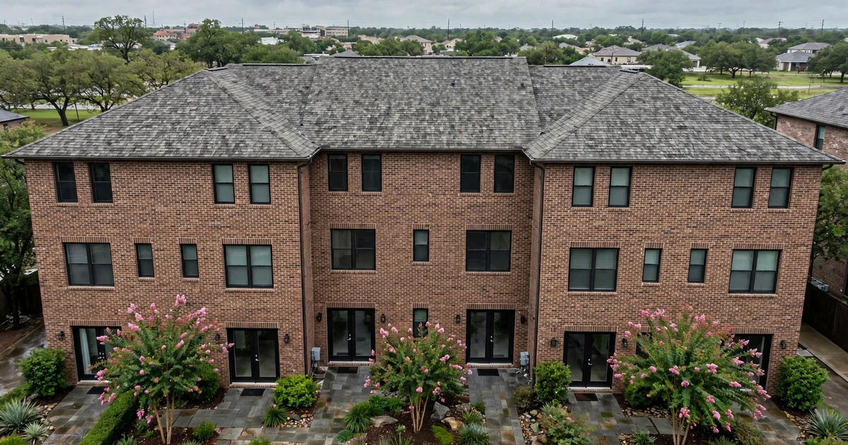 Village Grove East Townhomes roof repair in Pasadena: elevated view of brick townhomes sharing a weathered gray architectural shingle roof, overcast
